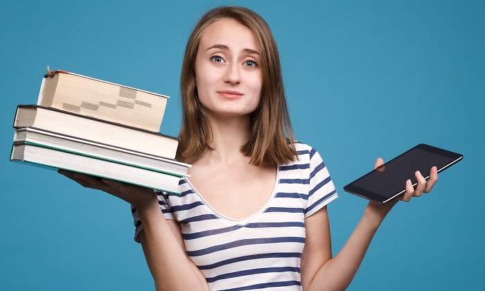 Una chica sostiene libros tradicionales en una mano y un ebook en la otra