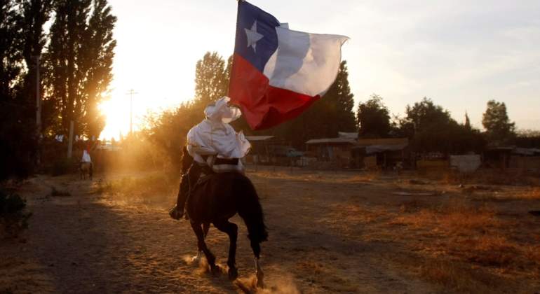 Una persona a caballo avanza con la bandera de Chile