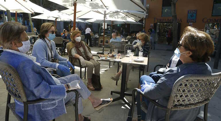 Mujeres tomando algo en una terraza con mascarilla