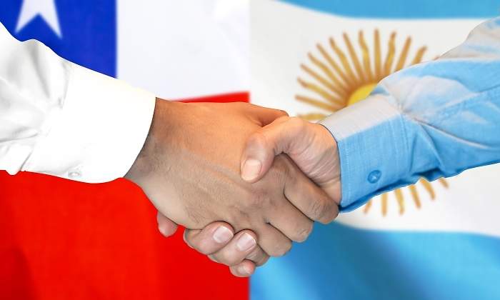 Apretn de manos con las banderas de Chile y Argentina de fondo